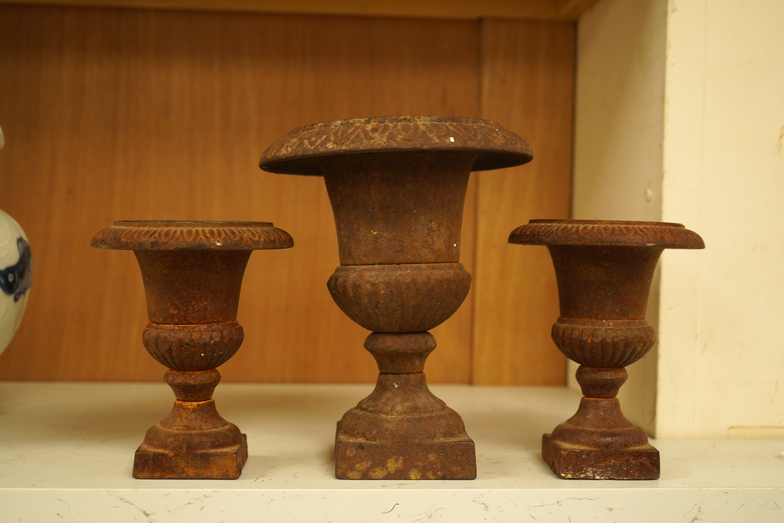 A garniture of three cast iron campana vases, largest 18cm high